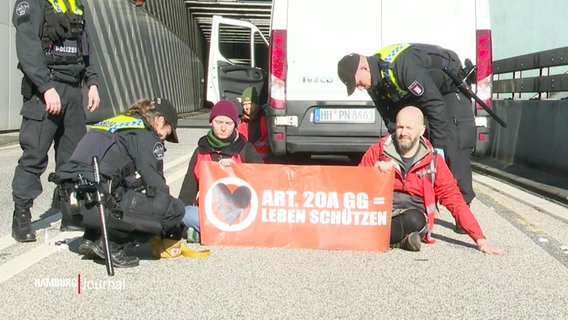 Klimaaktivisten umringt von Polizisten auf einer Autobahn. © Screenshot 