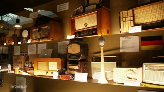 Auf einem Regal stehen mehrere historische Radiogeräte © Screenshot 