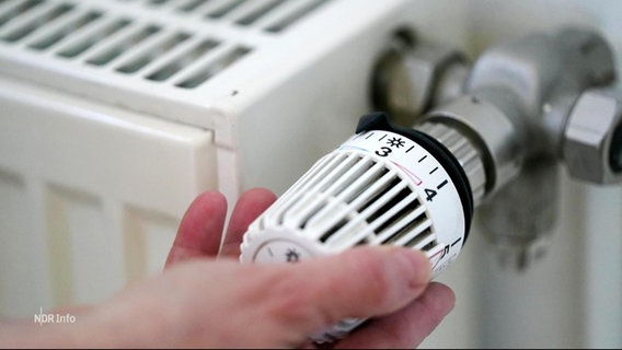 Eine Hand dreht den Thermostat einer Heizung. © Screenshot 