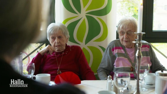 Zwei Seniorinnen sitzen nebeneinander an einem Tisch. © Screenshot 