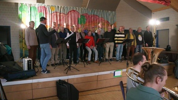 Der Shanty-Chor auf der Bühne begleitet von einem Symphonie-Orchester. © Screenshot 