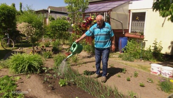 Ein Mann gießt seinen trockenen Garten. © Screenshot 