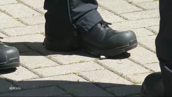 Polizeistiefel stehen auf einer Patronenhülse. © Screenshot 