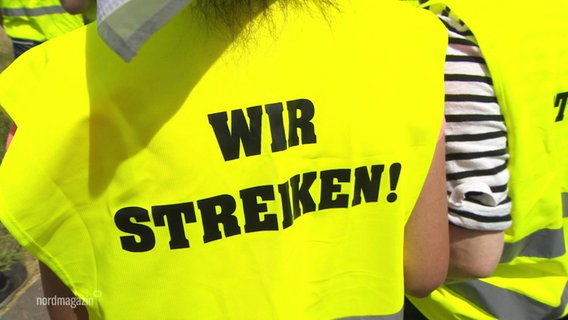 Gelbe Warnweste mit der Aufschrift "Wir streiken!" auf dem Rücken. © Screenshot 
