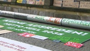 Auf der Straße liegende Demonstrationsschilder nach Klimaprotesten gegen den Bau des LNG-Terminals. © Screenshot 