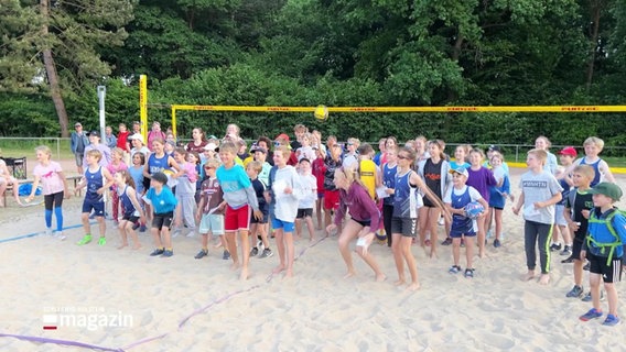 Viele Kinder stehen auf einem Beach Volleyball Feld. © Screenshot 