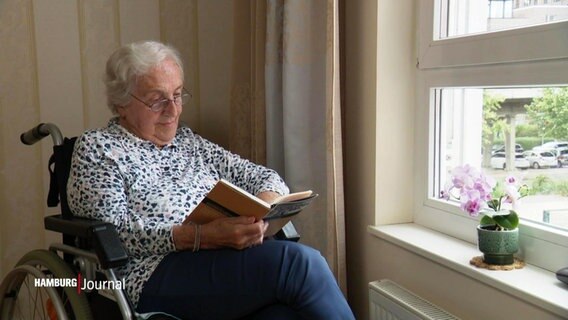 Eine ältere Dame sitzt an einem Fenster und liest ein Buch. © Screenshot 