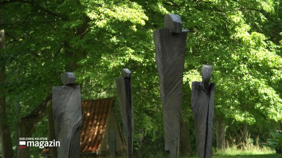Vier metallene Skulpturen mit menschlicher Form, stehen in einem Park. © Screenshot 
