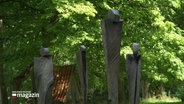 Vier metallene Skulpturen mit menschlicher Form, stehen in einem Park. © Screenshot 