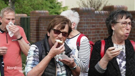Touristen essen Häppchen auf einer Stadtführung durch Ueckernmünde. © Screenshot 
