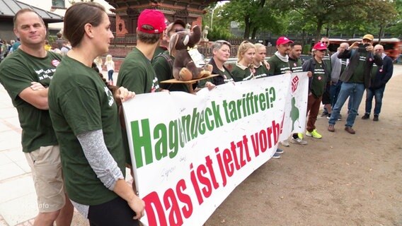 Streikende Mitarbeiter des Tierparks Hagenbeck halten ein Banner. © Screenshot 