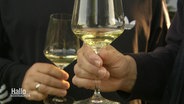 Zwei Menschen halten Gläser mit Weißwein in den Händen. © Screenshot 