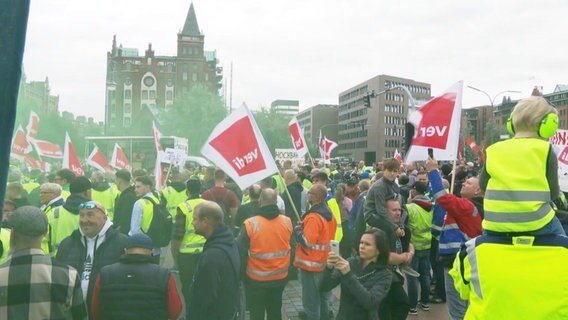 HHLA-Mitarbeitenden schwingen ver.di-Fahnen auf einer Demo. © Screenshot 