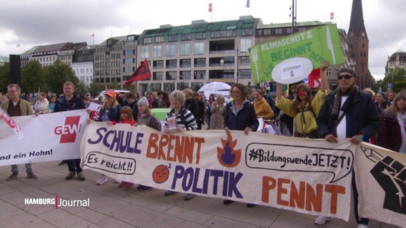 Demonstrierende halten ein Transparent hoch mit dem Spruch "Schule brennt, Politik brennt". © Screenshot 