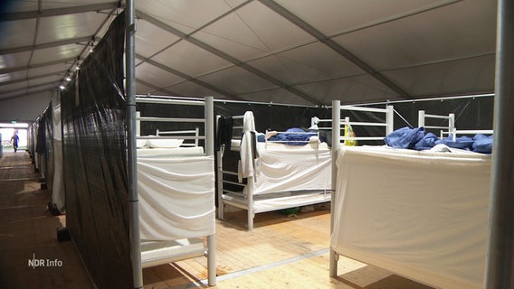 Betten in einer improvisierten Unterkunft für geflüchtete Menschen. © Screenshot 