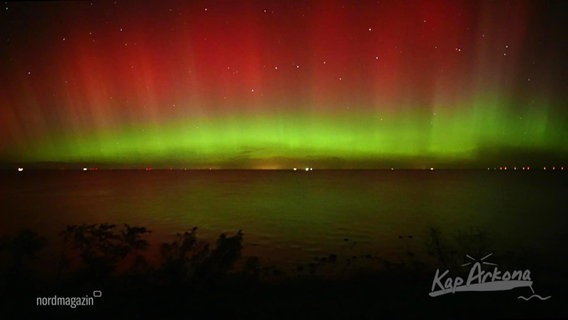An einem dunklen Himmel sind strahlende rote und grüne Lichter zu sehen. © Screenshot 