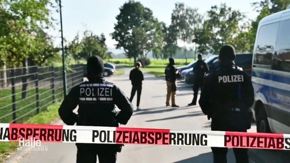 Polizeibeamte stehen vor Absperrband. © Screenshot 