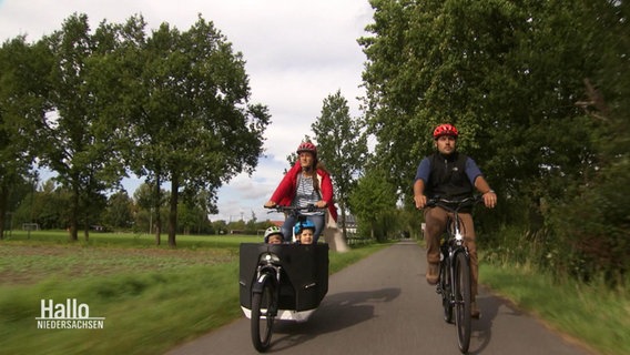 Ein junges Elternpaar fährt mit dem Fahrrad, und ihren Kindern vorne im Lastenrad, durchs Wendland. © Screenshot 