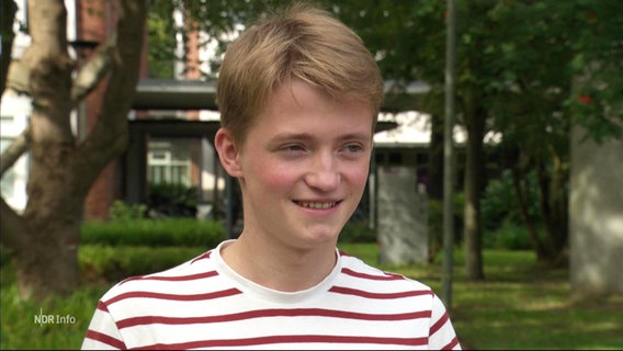 Ein lächelnder blonder junger Mann mit geringeltem Shirt © Screenshot 