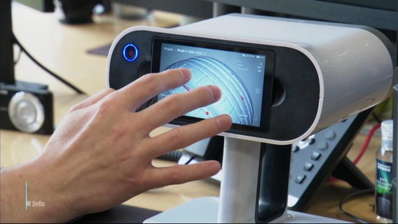 Eine Hand berührt einen kleinen Bildschirm, auf dem ein animierter Autoreifen zu sehen ist © Screenshot 