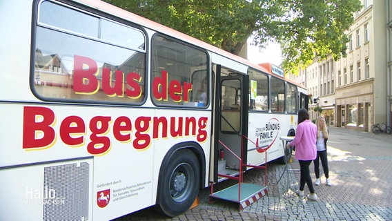 In einer Fußgängerzone ist ein Bus geparkt mit der Aufschrift "Bus der Begegnung". © Screenshot 