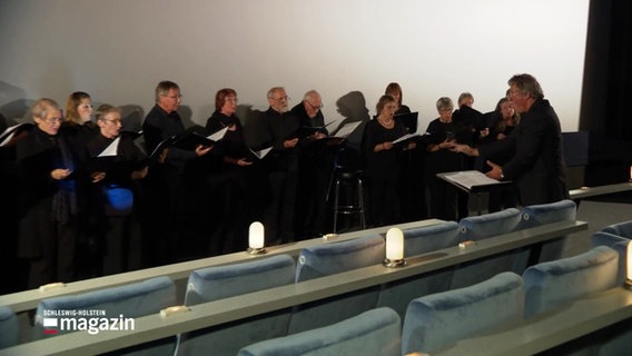 Ein Chor singt vor einer Kino-Leinwand © Screenshot 