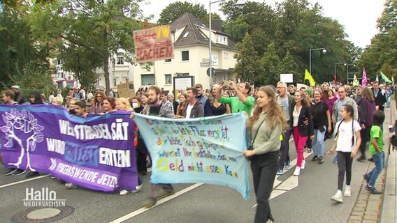 Protestierende Menschen tragen Banner und Schilder. © Screenshot 