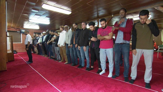 Muslime stehen in einer Reihe, während eines Mittagsgebets. © Screenshot 