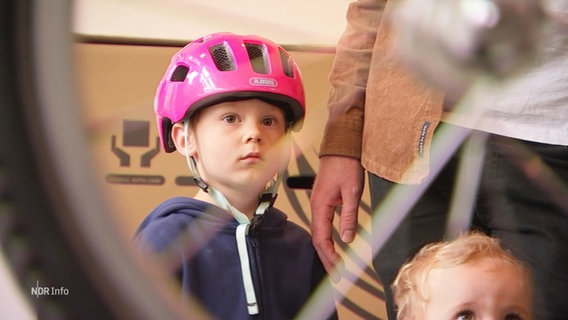 Der kleine Kalle schaut bei der Reperatur seines Fahrrads zu, er trägt einen pinken Helm. © Screenshot 