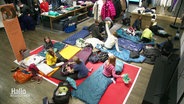 Kinder haben es sich auf Matratzen und Isomatten in Schlafsäcken in einer Ecke eines Bekleidungsgeschäfts gemütlich gemacht. © Screenshot 