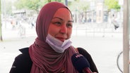 Eine Frau mit Hijab und Mund-Nasen-Schutzmaske spricht bei einer Straßenumfrage in ein Mikrofon. © Screenshot 