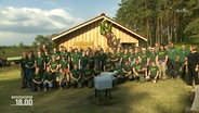 Eine große Gruppe Freiwilliger vor dem selbst gebauten Landjugendhaus in Amelinghausen. © Screenshot 