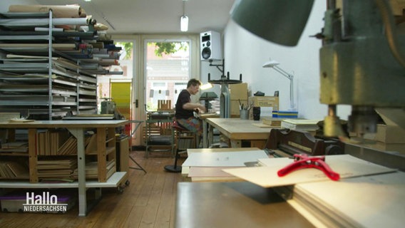 Ein Buchbinder sitzt an seinem Arbeitstisch. © Screenshot 
