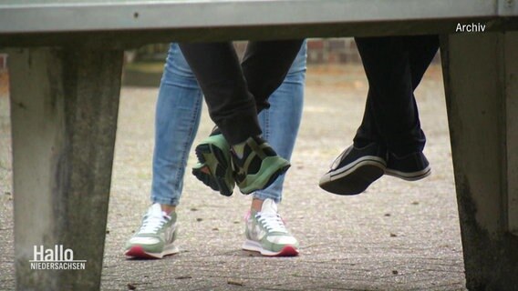 Die Beine und Füße von Jugendlichen, die auf einer Tischtennisplatte sitzen. © Screenshot 