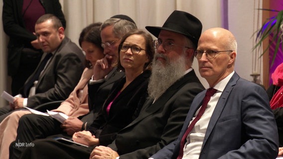 Peter Tschentscher, Shlomo Bistritzky und weitere Gäste sitzen neben einander bei einer Veranstaltung. © Screenshot 