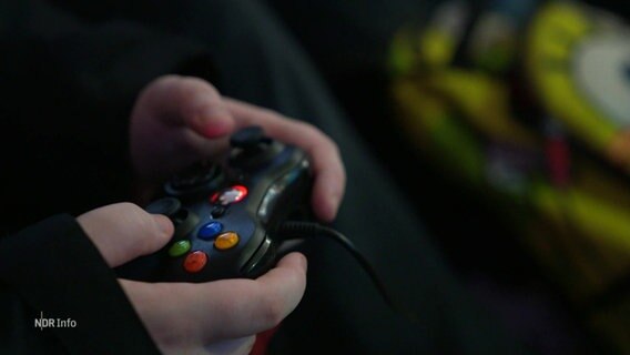 Eine Hand mit einer Spielkonsole. © Screenshot 