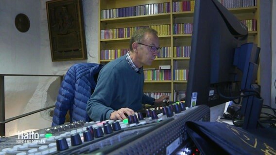 Hermann Haarmann sitzt an einem Schreibtisch und blickt auf einen Bildschirm. © Screenshot 
