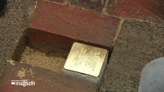 Ein Stolperstein in einer Öffnung in der Straße, neben ihm ist Platz für einen zweiten Stein. © Screenshot 