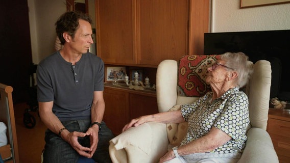 Moderator Jo Hiller unterhält sich mit einer älteren Dame, die in einem Ohrensessel in einem Apartment eines Pflegeheims sitzt. © Screenshot 