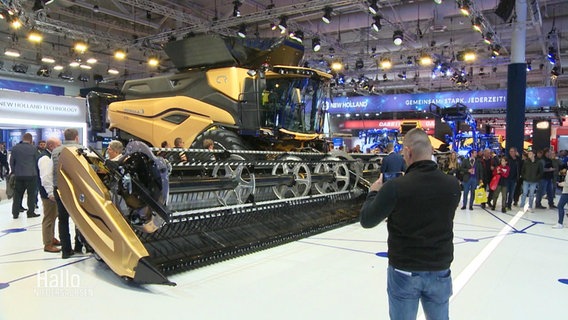 Ein Besucher der Agritechnica in Hannover fotografiert eine riesige Landmaschine. © Screenshot 