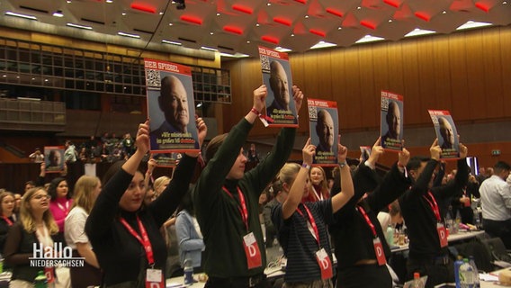 Juso-Mitglieder halten Drucke des "Spiegel"-Covers mit Kanzler Scholz in die Höhe, um eine Zeichen gegen die Migrationspolitik zu setzen. © Screenshot 