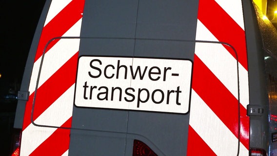 Ein Schild auf einem Fahrzeug warnt vor Schwerlasttransport. © Screenshot 