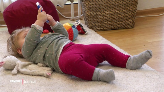 Ein Baby betrachtet einen Greifring. © Screenshot 