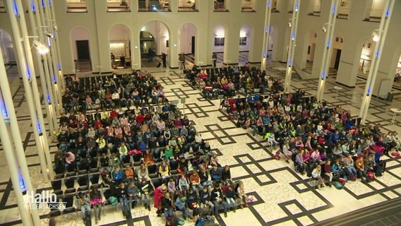 Kinder sitzen in einem großen Hörsaal. © Screenshot 