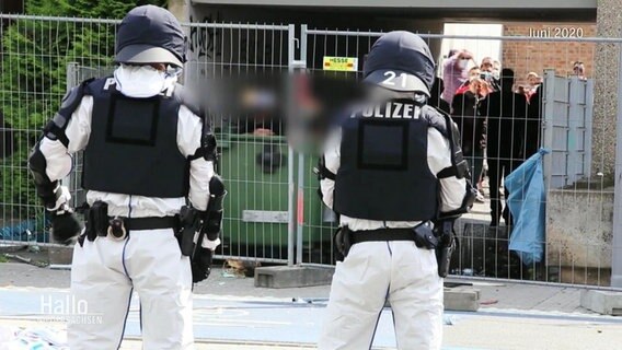 Polizeibeamte stehen vor von ihnen abgeriegeltem Wohnhochhaus. © Screenshot 