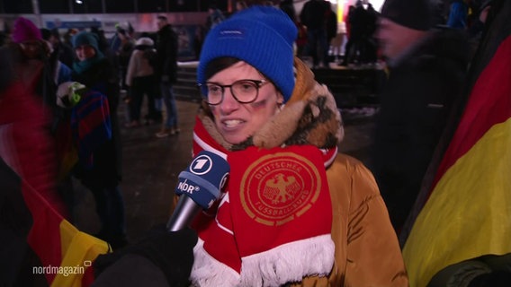 Eine Person mit Deutschland Fan-Artikeln im Interview. © Screenshot 