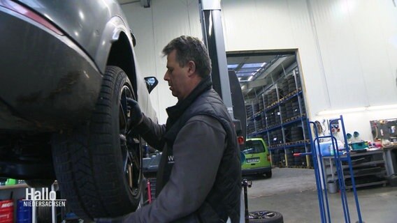 Ein Mechaniker wechselt an einem Auto auf der Hebebühne die Reifen. © Screenshot 