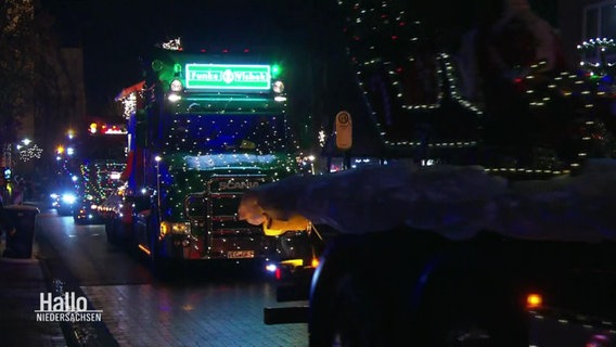 Ein Konvoi mit beleuchteten und dekorierten Lkws fährt durch die Dunkelheit. © Screenshot 