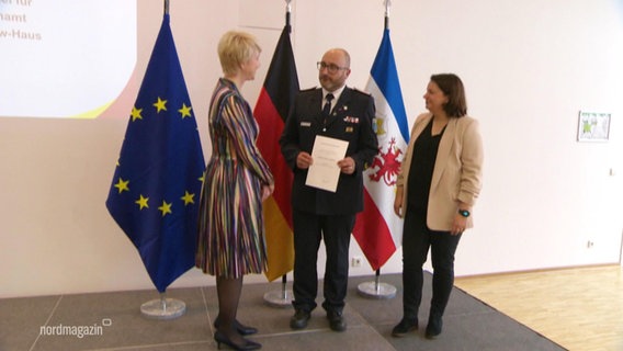 Manuela Schwesig steht einem Mann mit Urkunde in der Hand gegenüber. © Screenshot 