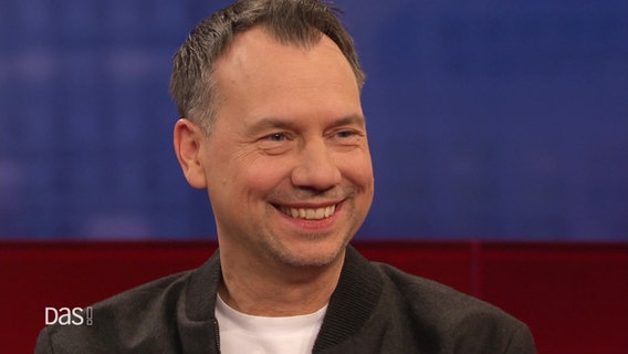 Sebastian Fitzek sitzt bei DAS! auf dem roten Sofa. © Screenshot 